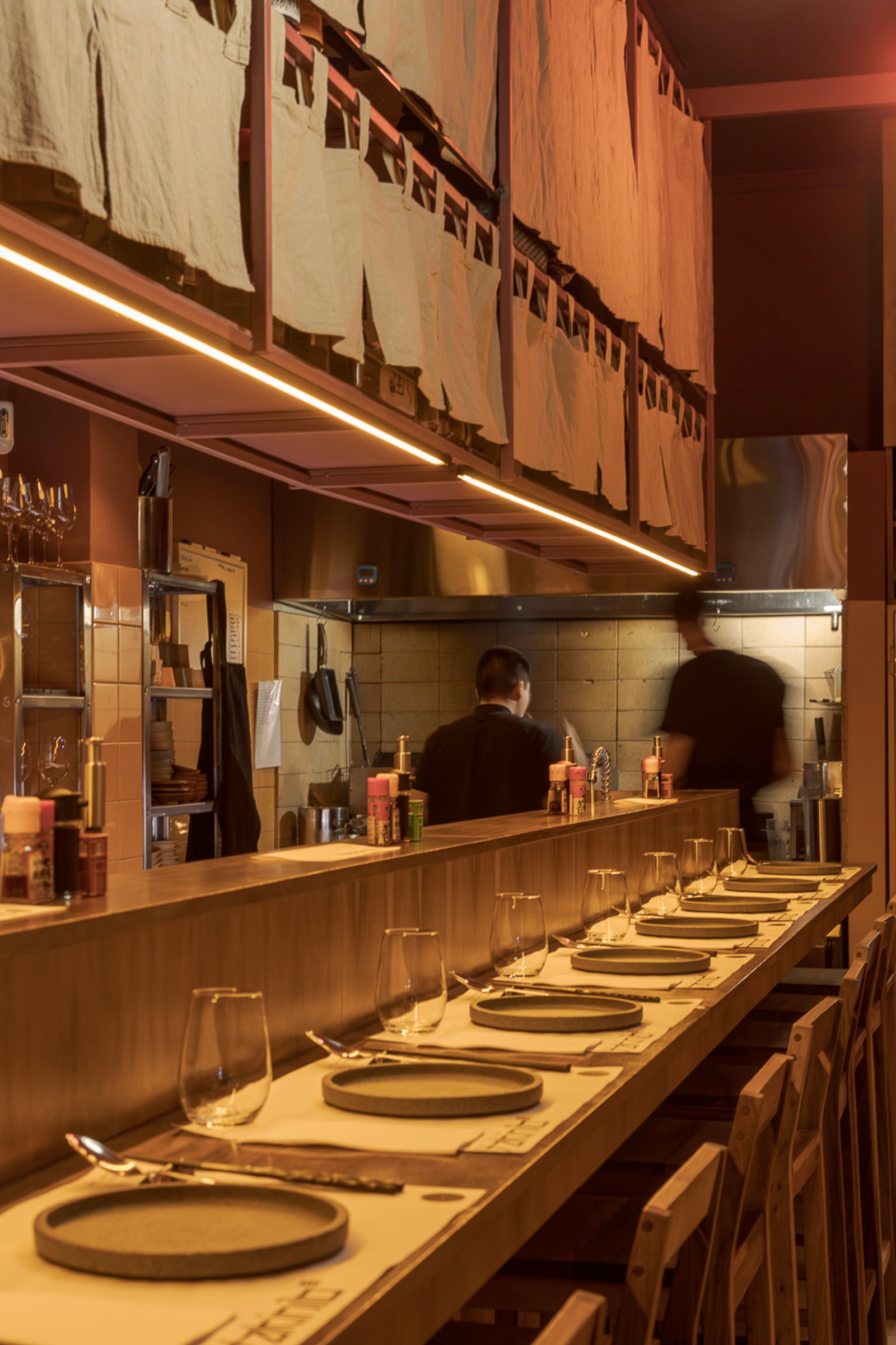 Interior de restaurante japonés con barra, cocina a la vista y luces cálidas — proyecto Yakinilo, por Estudio YME, en Av. Dorrego 1551